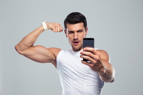Sports man making selfie photo on smartphone over gray background