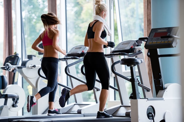 sport, fitness, lifestyle, technology and people concept - smiling woman exercising on treadmill in gym