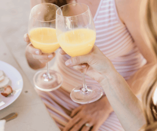 Two women cheers a mimosa at brunch