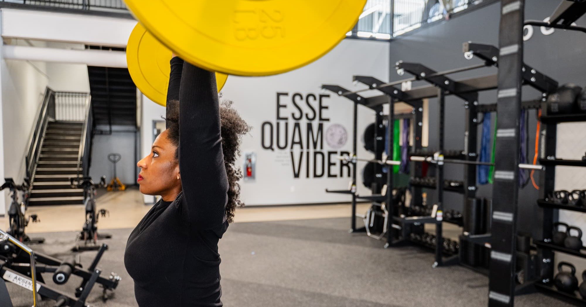 woman lifting weights in a overhead press inside O2 Fitness Clubs