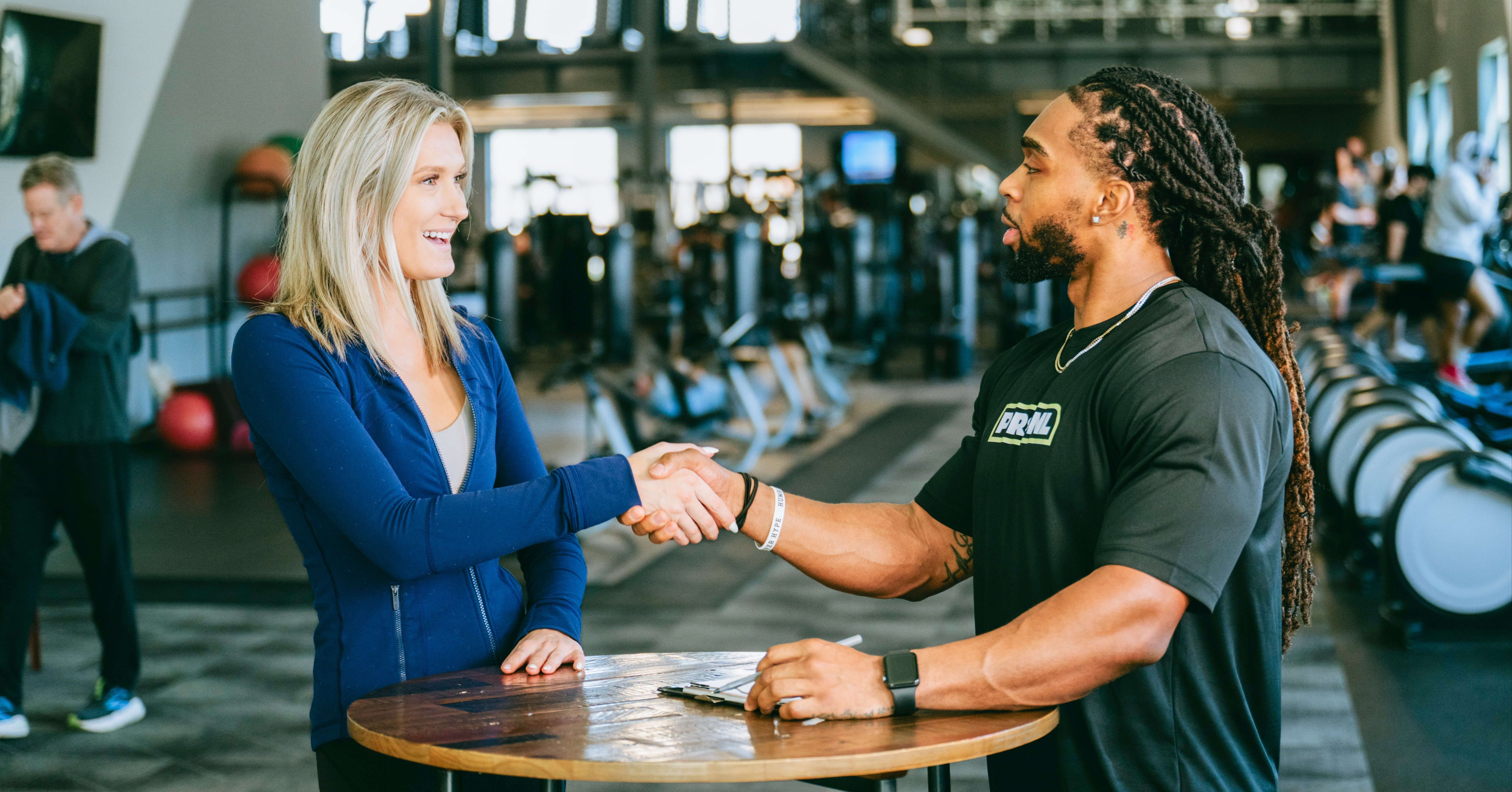 Young woman shaking hands with male personal trainer after a successful consultation session 