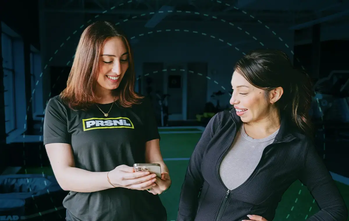 female personal trainer showing a female training client O2 Fitness Clubs new PRNSL training app
