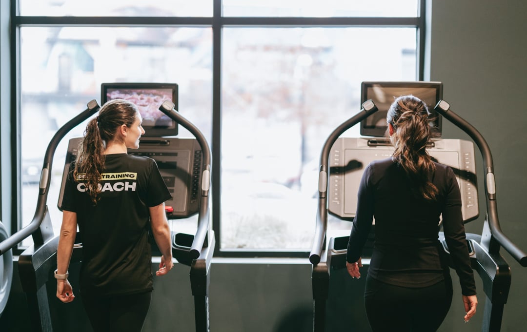 two women walking on a treadmill for cardio
