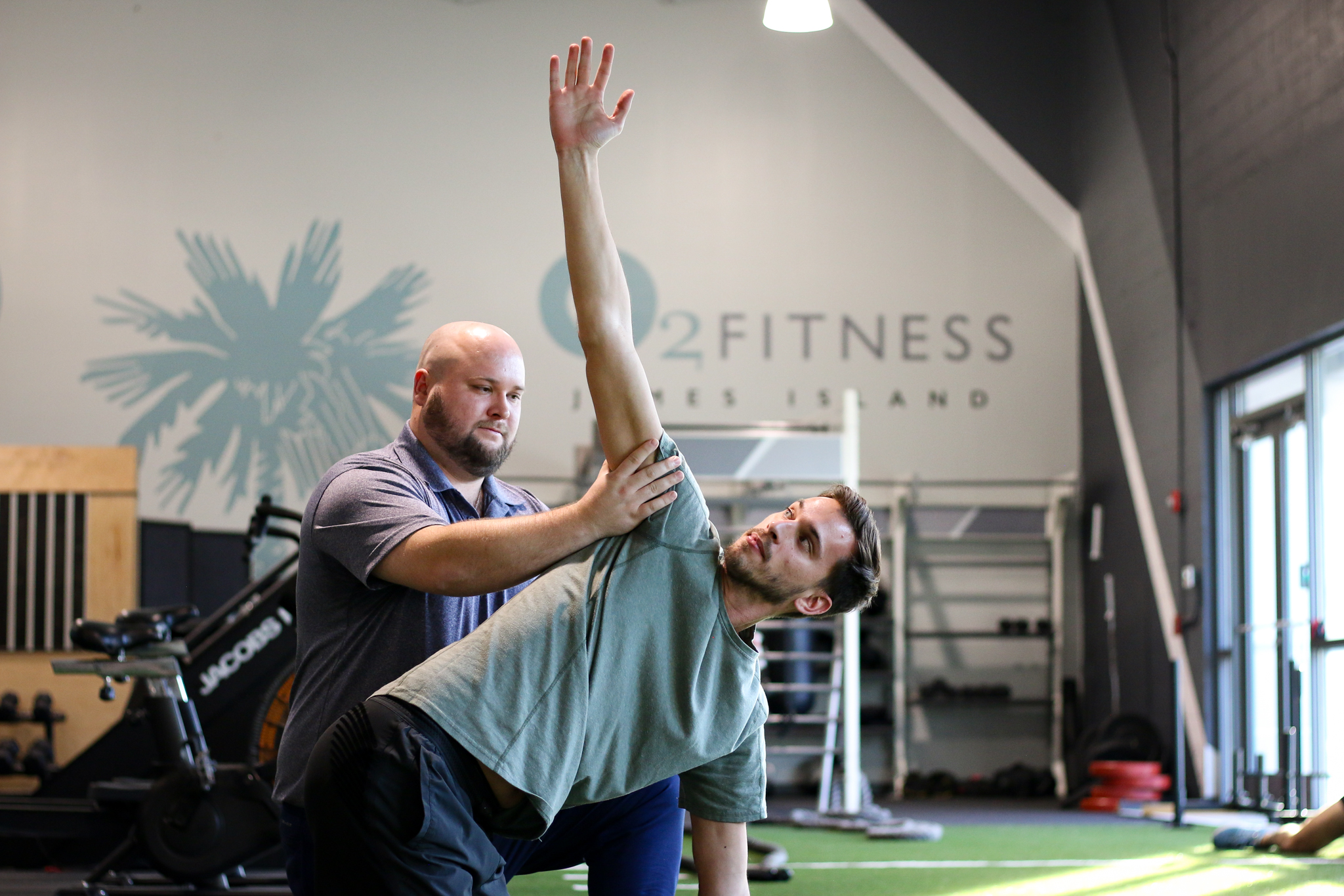 a physiotherapist and male client doing mobility exercises on the turf in inside O2 Fitness Clubs James Island location