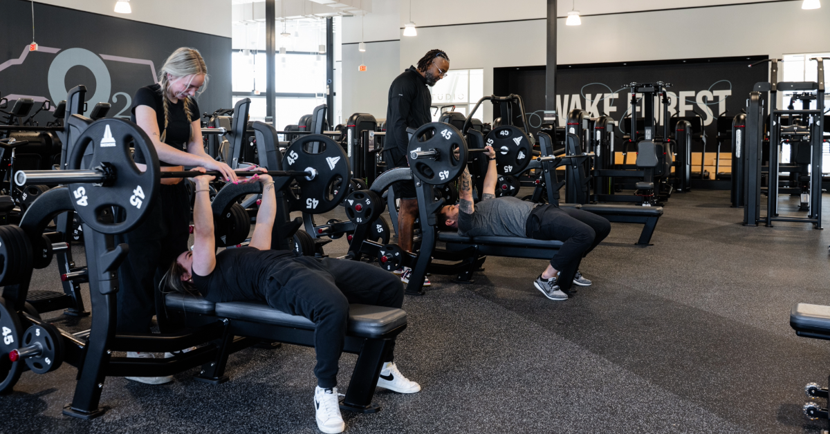 one man and woman bench pressing with a male and female spotter inside o2 fitness clubs