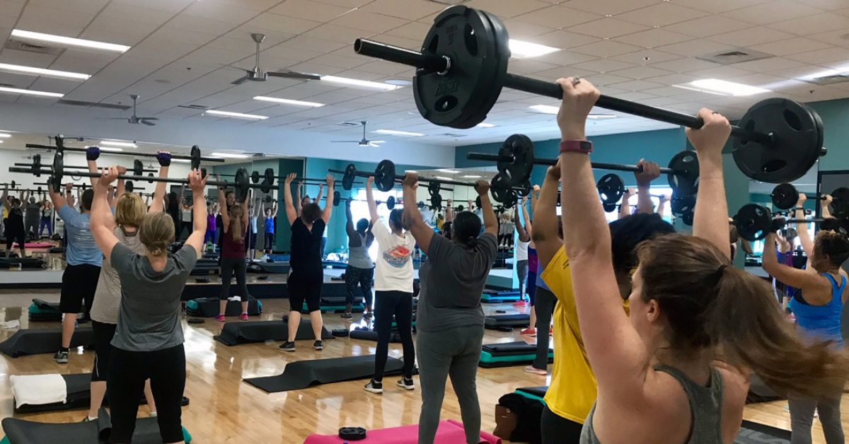 a room full of men and women inside a group fitness studio at o2 fitness clubs during a bodypump class