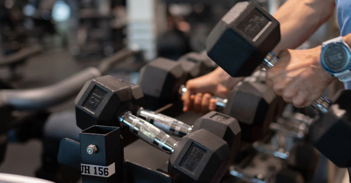 man lifting dumbbells off a rack inside an O2 Fitness Clubs