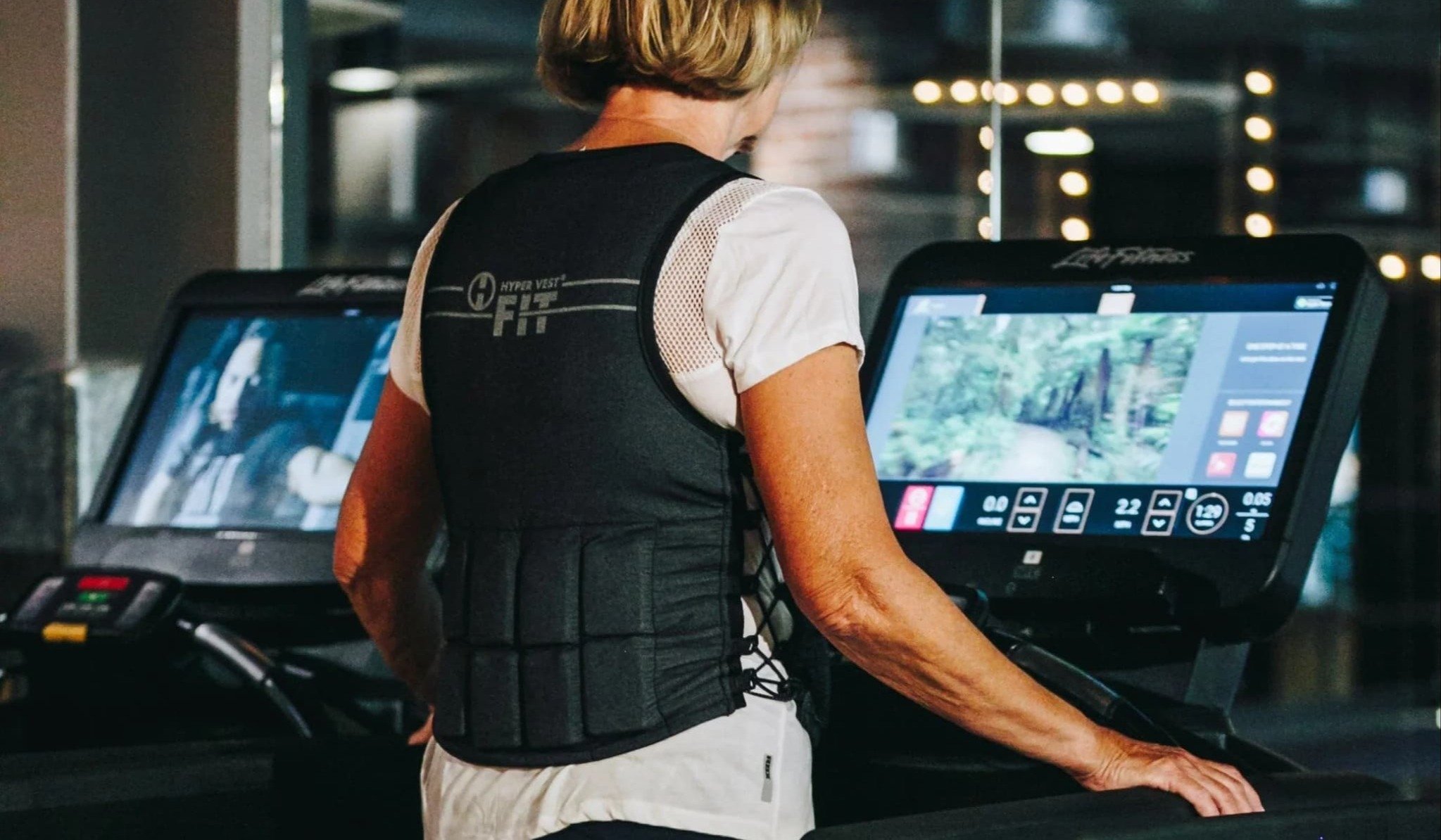 a woman walking on a treadmill wearing a weighted vest